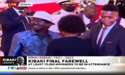 Shock as Kibaki’s Grandson Refuses to Greet Raila at Burial, Hides His Face From Him