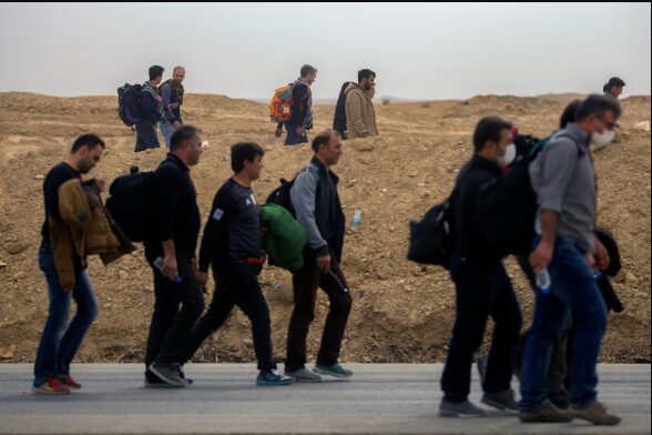 Refugees walking along a rural path carrying their belongings during global migration in 2025.