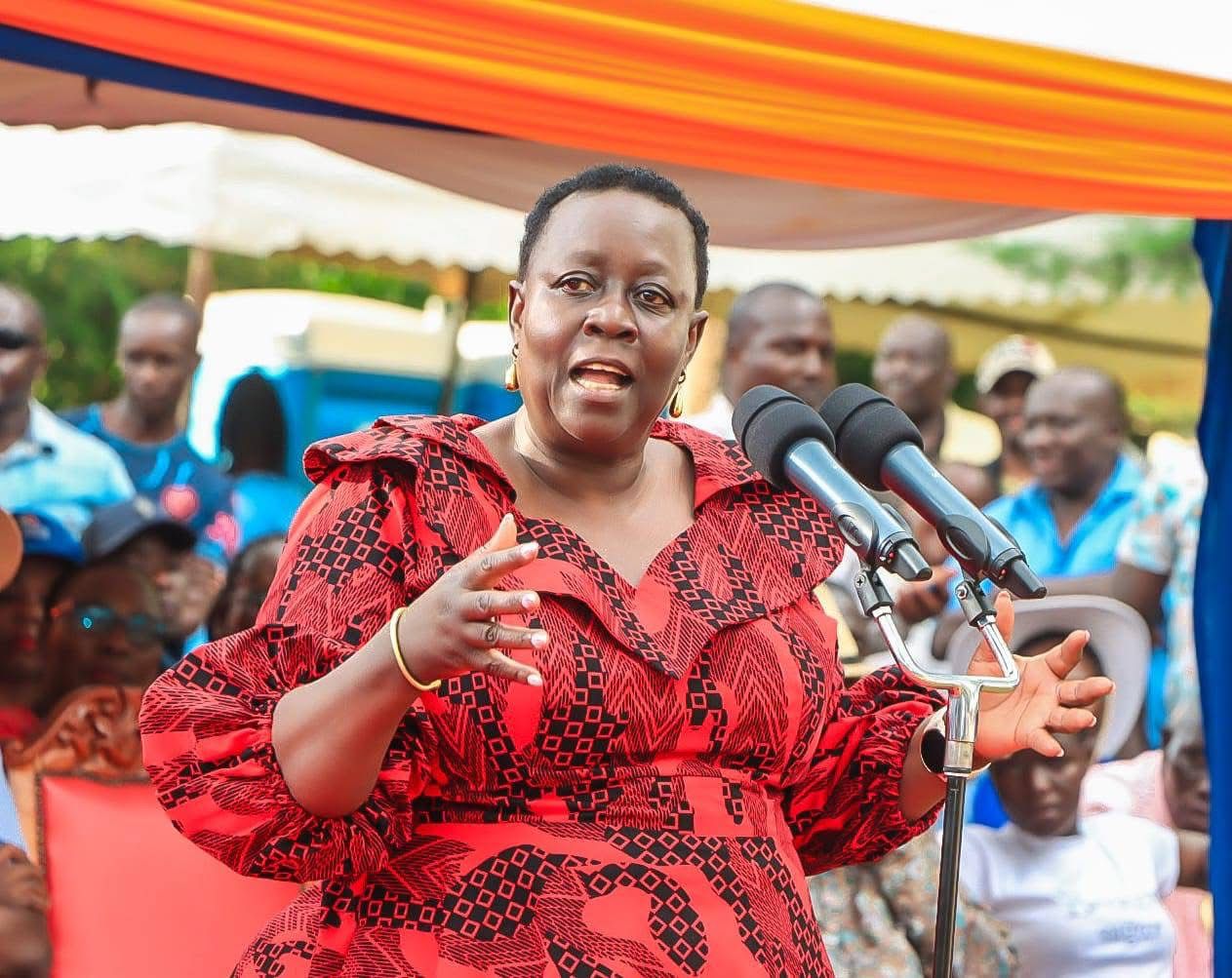 Ruth Odinga standing behind a podium, speaking to a crowd at a political event in Kenya.