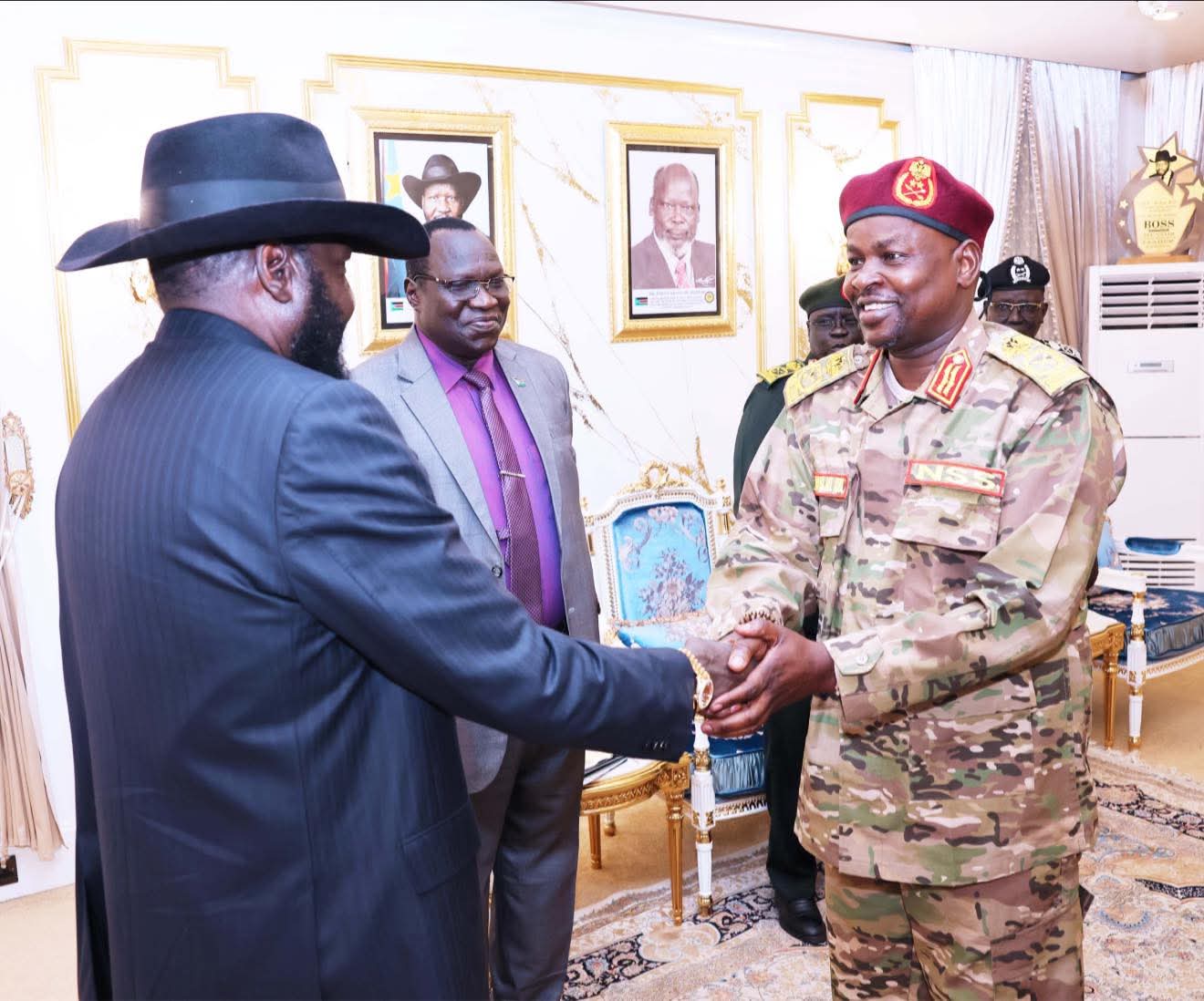 South Sudan President Salva Kiir (black hat) shaking hands with then-Vice President and General Benjamin Bol Mel (military uniform) in a formal Juba office.
